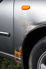 Corrosion of the car. Rust, corroded gray paint on the front fender of the car. Vertical photo.