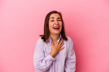 Middle age caucasian woman isolated on pink background laughs out loudly keeping hand on chest.