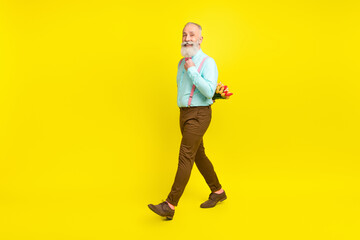 Full length body size photo old man keeping tulips flowers going on date isolated bright yellow color background