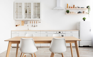 Modern design scandinavian kitchen. White kitchen furniture and dining table with chairs, utensils and kitchenware