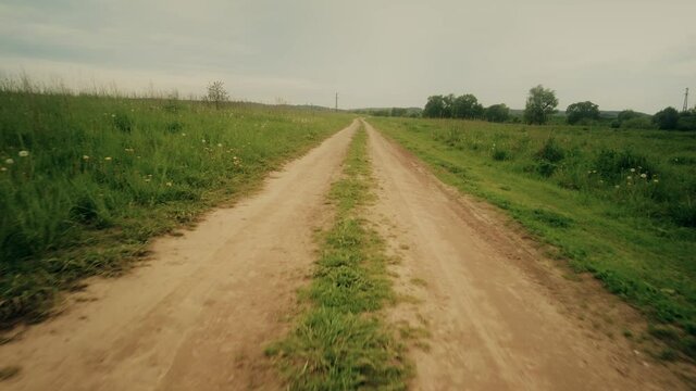 POV shot, moving along the rural field pathway in summer