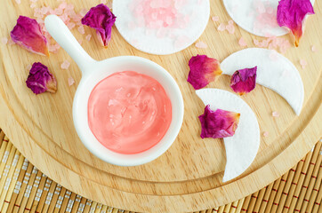 Small porcelain bowl with rose jelly face or eye mask, cotton eye patches and dry rose petals....