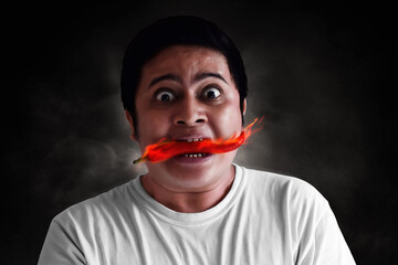 Portrait of young man eating chili pepper