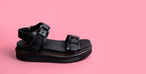 Black leather summer womens sandals on pink background flat lay copy space. Fashionable casual stylish trendy female shoes, rough sandals with thick soles. Minimalistic concept, foot advertising