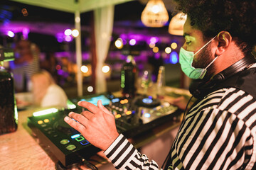 African dj playing music at cocktail bar outdoor while wearing face safety mask - Entertainment,...