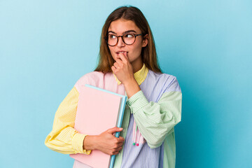 Young caucasian student woman holding books isolated on blue background relaxed thinking about something looking at a copy space.