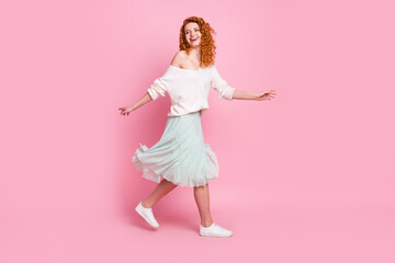 Full length body size photo of pretty girl with red hair going on walk wearing spring outfit isolated on pastel pink color background