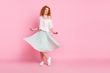 Full length body size photo of red hair girl laughing in skirt dancing spinning at party isolated on pastel pink color background