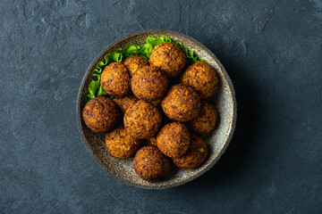 falafel balls in a ceramic bowl on a black background, top view