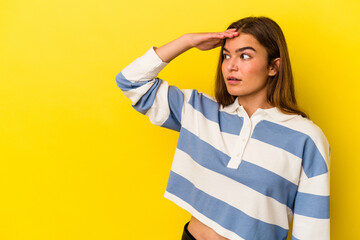 Young caucasian woman isolated on yellow background looking far away keeping hand on forehead.