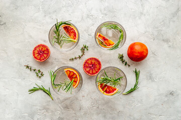 Red orange lemonade in glasses with ice and rosemary