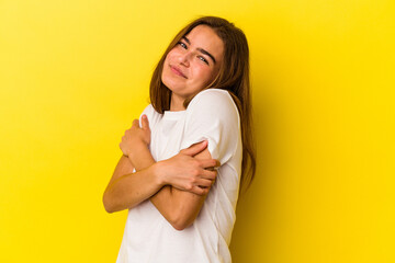 Young caucasian woman isolated on yellow background hugs, smiling carefree and happy.