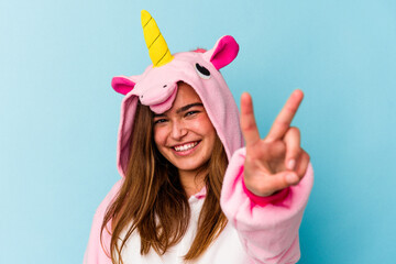 Young caucasian woman wearing an unicorn pajama having fun isolated on blue background