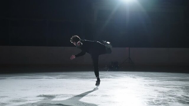 Professional male figure skater performs a complex figure skating element flawlessly. Athlete performs a Bedouin jump in training. Young man performs a butterfly jump in figure skating. Skating jump.