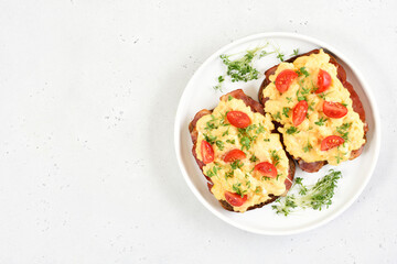Scrambled eggs with microgreen, bacon and tomatoes on bread