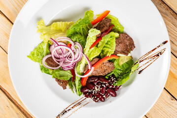 salad with beef, red beans and vegetables, wooden background