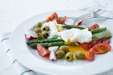 Poached egg, asparagus green olives, tomatoes and reddish. Keto vegetarian breakfast. 