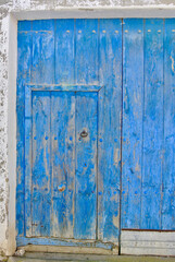 Fototapeta na wymiar Old blue barn door in the countryside. Closed shabby vintage entrance to the village yard.