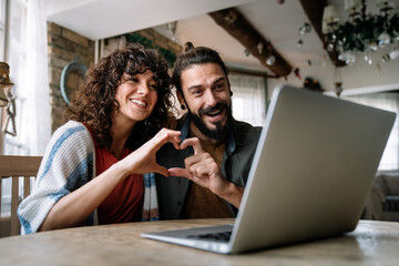 Young smiling couple having online family video call at home