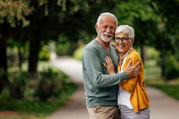Senior couple, happily posing for the camera, in the park.