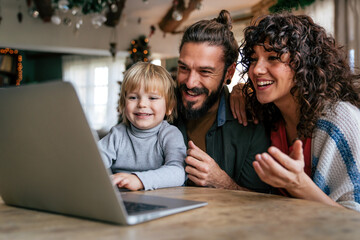 Happy young family making video call with laptop at home