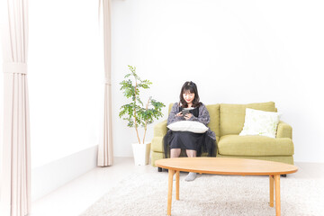 家でスマートフォンを使う若い女性