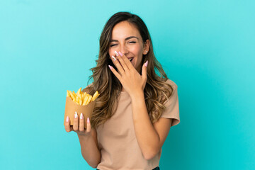 Young woman holding fried chips over isolated background happy and smiling covering mouth with hand