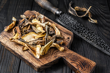 Sliced Porcini wild dried mushrooms on a wooden cutting board. Black wooden background. Top view