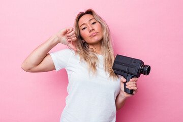 Young australian woman filming with a vintage video camera isolated feels proud and self confident,...