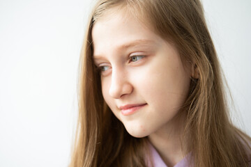 portrait of beautiful teenage girl with long hair in purple hoodie standing against white wall
