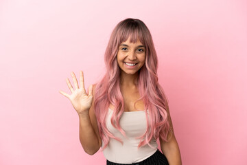 Young mixed race woman with pink hair isolated on pink background counting five with fingers