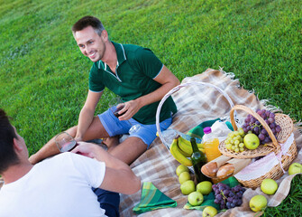 Happy cheerful man enjoying life on picnic outdoors with his friend