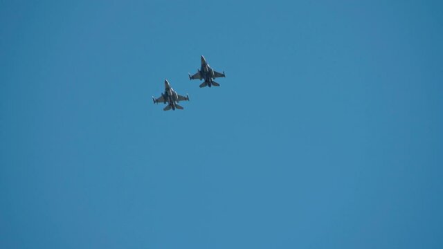A squadron of F 16 military fighters, on parade, fly by quickly in figures, demonstrating power and strength.
