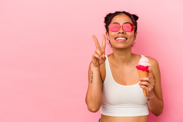 Young latin woman holding an ice cream isolated on pink background showing number two with fingers.