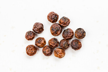 several red kampot peppercorns close up on gray