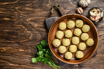 Fototapeta na wymiar Fresh Raw falafel balls in a wooden plate. Wooden background. Top view. Copy space