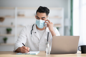 Doctor in face mask working in clinic, having phone call