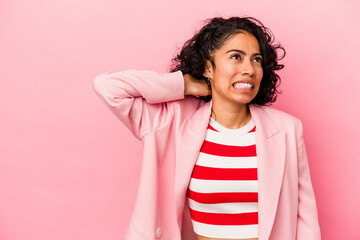 Young trendy latin woman isolated on pink background touching back of head, thinking and making a...
