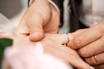 cropped view of man putting wedding ring on finger of bride, blurred foreground