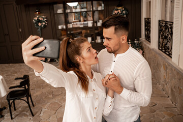 displeased woman looking at boyfriend while taking selfie in restaurant