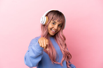 Young mixed race woman with pink hair isolated on pink background listening music