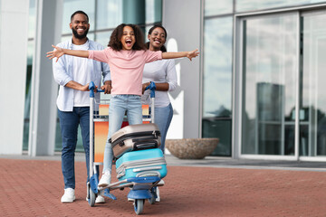 Happy black family traveling with kid, having fun in airport - obrazy, fototapety, plakaty