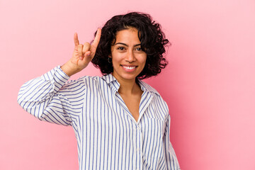 Young curly latin woman isolated on pink background showing a horns gesture as a revolution concept.