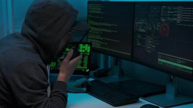Computer hacker typing code on keyboard late night working and bypassing cyber security. The player uses a walkie-talkie