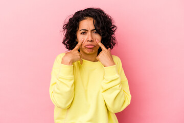 Young curly latin woman isolated on pink background crying, unhappy with something, agony and confusion concept.