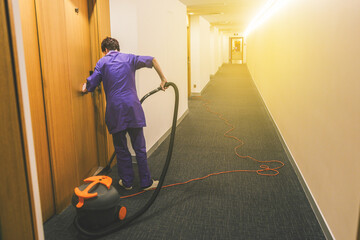 Woman is cleaning the hotel room. Hotel cleaning services. Working as a maid at the hotel. Long...