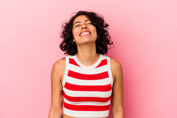 Young curly latin woman isolated on pink background laughs and closes eyes, feels relaxed and happy.