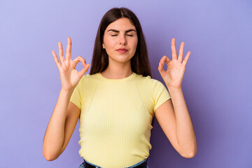 Young caucasian woman isolated on purple background relaxes after hard working day, she is performing yoga.