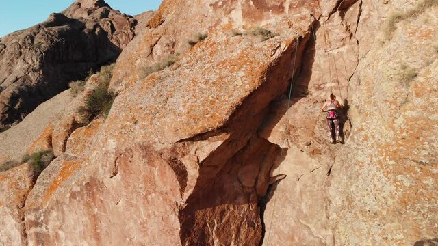 Young woman climbing on the high rock
