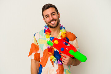 Young caucasian woman on a hawaiian party holding a water gun isolated on white background happy,...